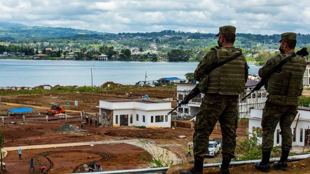 Philippine soldiers looking over workers constructing a building which was a main battleground in 2017 when Islamic State-inspired Muslim militants laid siege to the southern Philippine city of Marawi.