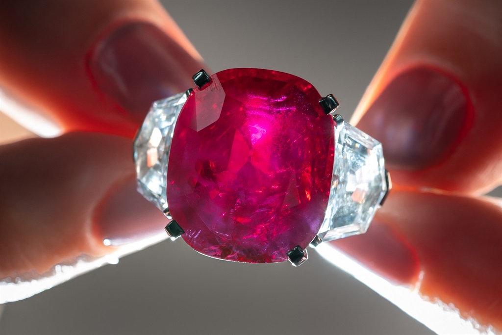 This photograph taken on May 8, 2023, shows an employee of Christie's auction house holding the "Sunrise Ruby" a rare Cartier ruby and diamond ring, which weighs in at 25.59 carats and is expected to fetch at least 14 million USD at the World of Heidi Horten sale in Geneva. 