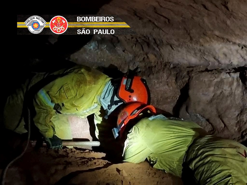 Handout picture released from Sao Paulo State's Military Police on October 31, 2021 showing firefighters working to rescue civilian firefighters buried in a cave after a collapse in Altinopolis, Sao Paulo state, Brazil.  