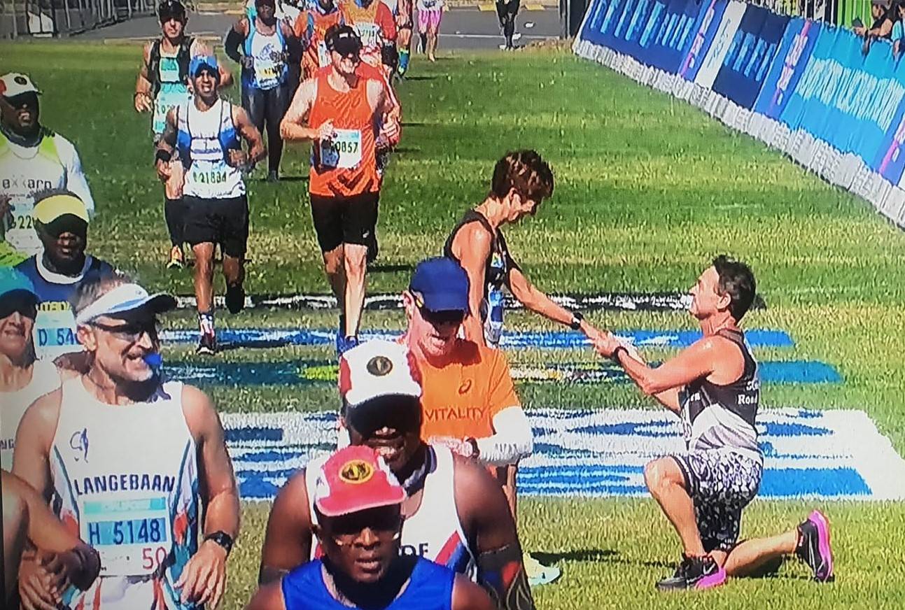 Kort voordat Colin Bosch vir die 20ste keer oor die eindstreep van die Twee Oseane-ultramarathon in Kaapstad gedraf het, het hy eers sy vriendin, Sharon Eldridge, gevra om te trou. Die oomblik is regstreeks op televisie uitgesaai.  Foto: Skermgreep