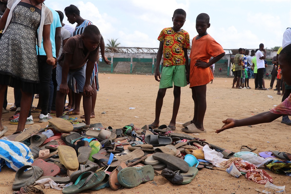 People search through piles of shoes left at a field in Monrovia after a stampede broke out. (Emmanuel Toby, AFP)