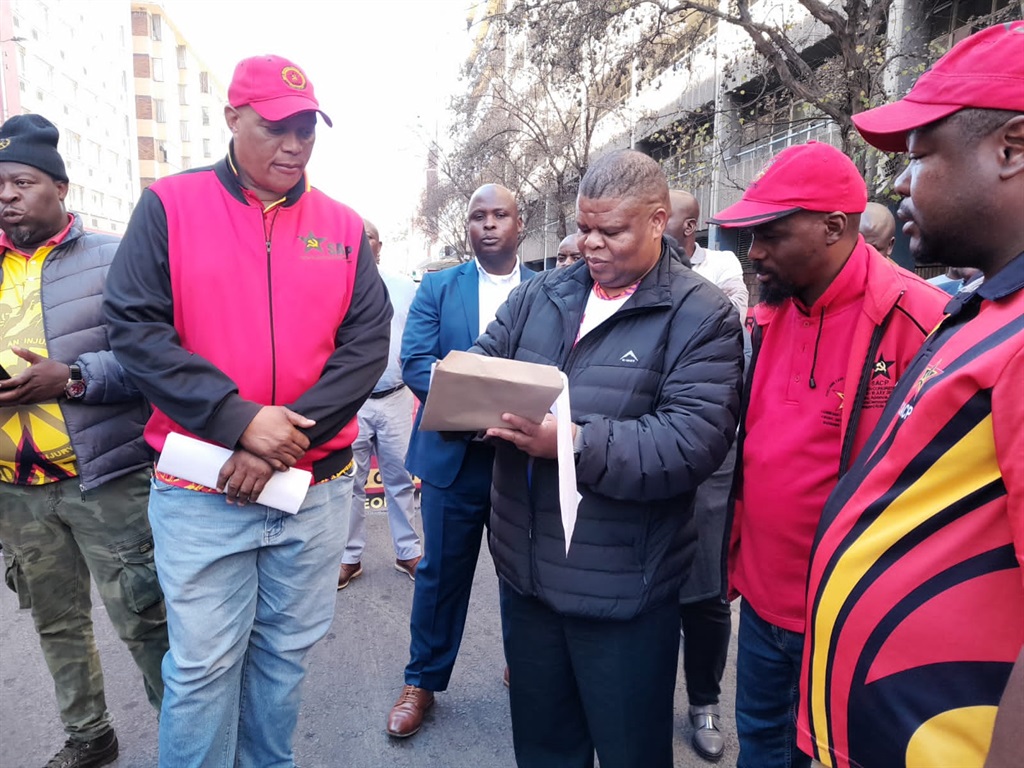 Deputy minister of water and sanitation, David Mahlobo (middle), signing a memorandum from members of the SACP in Tshwane.  