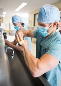 Medical staff sterilizing hands and arms before surgery from Shutterstock