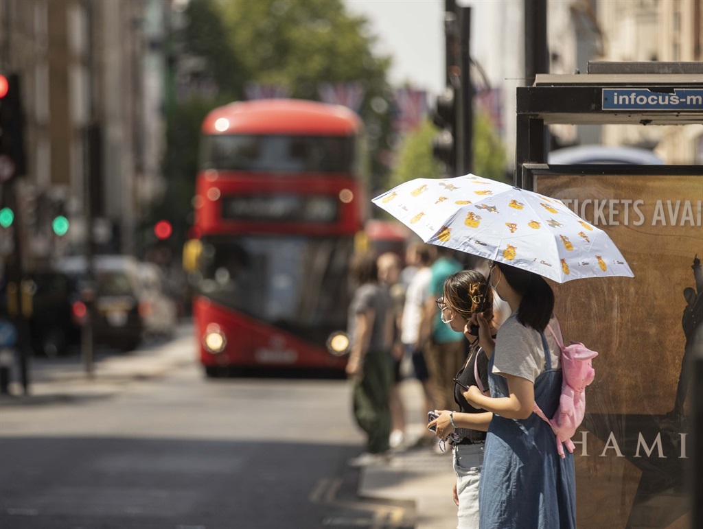  Women holding umbrella to protect from the Sun, wait at the bus stop as heatwave hits London, United Kingdom on July 18, 2022. The UK Meteorological Service (Met Office) issued an extreme temperature warning that temperatures could reach 40 degrees Celsius, posing a serious risk on health. The "red" alert for extreme temperatures that affect adversely travel, health services and education will last until July 19th. (Photo by Rasid Necati Aslim/Anadolu Agency via Getty Images)