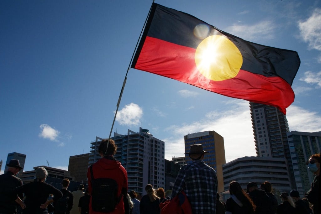 An Aboriginal flag is held aloft during a Black Lives Matter protest to express solidarity with US protesters and demand an end to Aboriginal deaths in custody, in Perth on 13 June 2020.