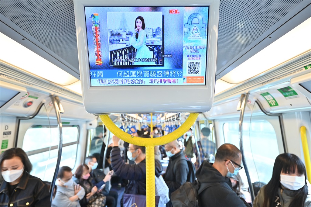 People watch a screen on a train showing news about Hong Kong model and influencer Abby Choi on 27 February, 2023 in Hong Kong.