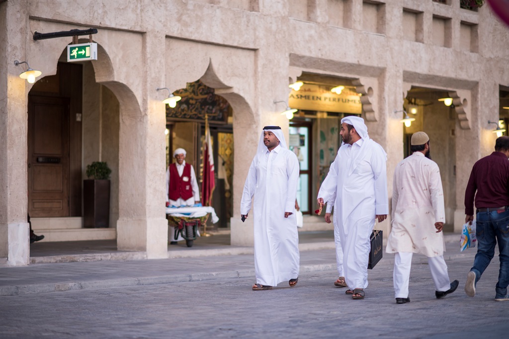 Qatari locals in traditional attire hang out in ol