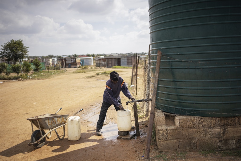 A man fills a jar with water from a tank in an inf