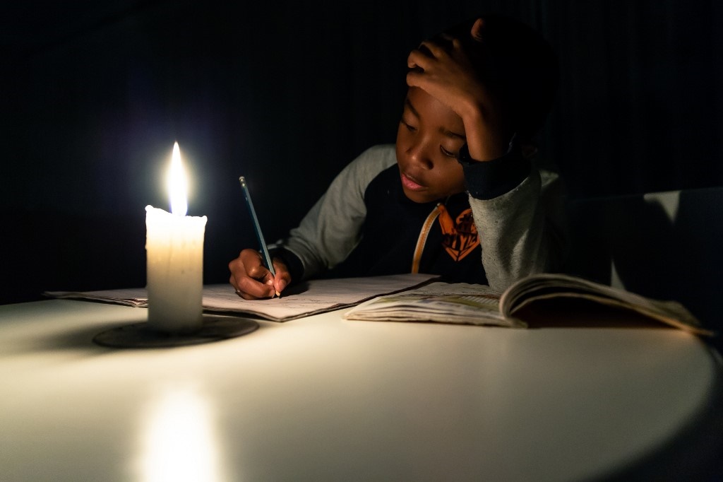 A young Zimbabwean boy does his homework under a candle light in Harare. (Jekesai Njikizana/AFP)