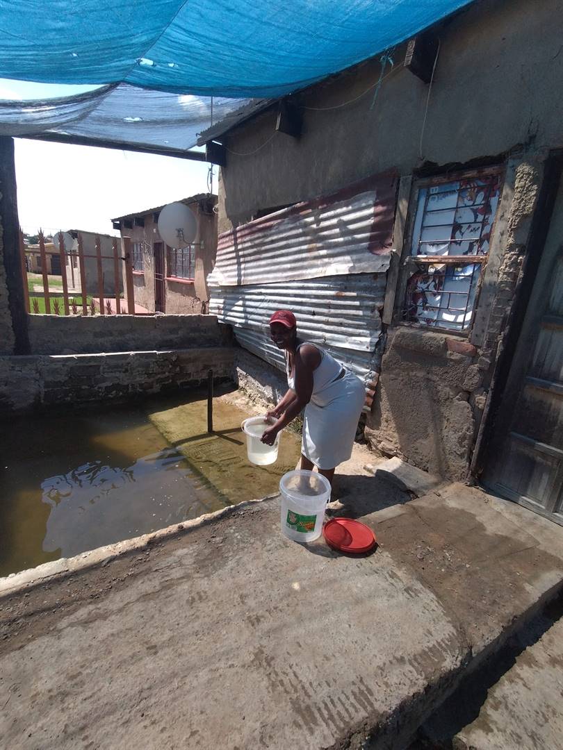 ’n Vrou in Tumahole, Parys, skep staande water langs haar huis in emmers om te gebruik. Mense in die provinsie skep ook water uit die veld omdat waterverskaffing in die meeste dorpe ’n probleem is.