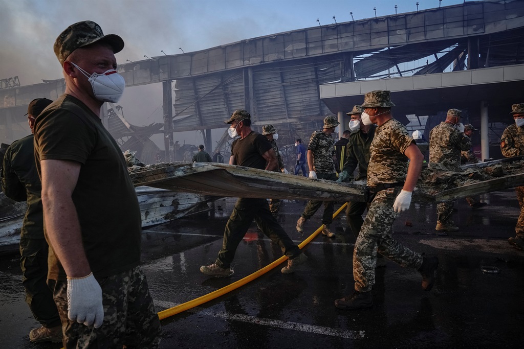 Reddingswerkers en soldate werk skouer teen skouer by 'n winkelsentrum wat deur 'n Russiese missiel getref is in Krementsjoek, in die Poltawa-streek. Krementsjoek is 'n industriële stad in die ooste van Oekraïne wat langs die Dnipro-rivier lê. Foto: Reuters

