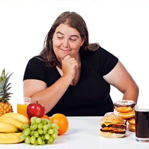 Woman deciding between fruit and junk food