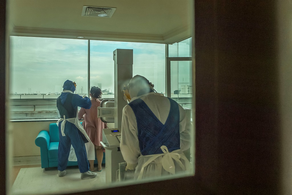 Health workers help a COVID-19 coronavirus patient (C) at Husada Utama hospital in Surabaya, East Java, on July 8, 2021. (JUNI KRISWANTO / AFP)