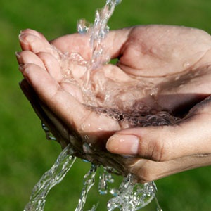 A woman holding her hands out for water from Shutterstock. 