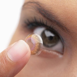 A woman putting in colored contacts from Shutterstock.