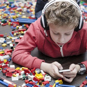 A child playing with his iPhone amidst a sea of Leggos from Shutterstock. 