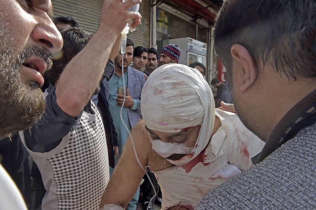 People help an injured man outside a hospital following a bomb blast at a mosque in Peshawar.