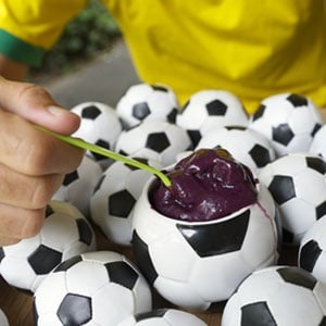Soccer player sits and eats açaí in a soccer ball-shaped bowl from Shutterstock.