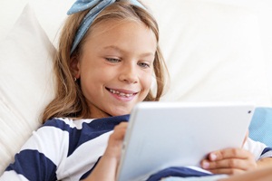 Child playing on tablet pc on the sofa at home from Shutterstock