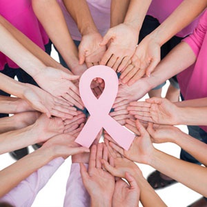 Hands joined in circle holding breast cancer struggle symbol from Shutterstock. 