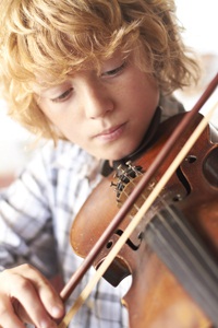 Boy Practicing Violin At Home from Shutterstock