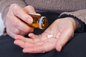 Close up of an elderly hand holding pills from Shutterstock