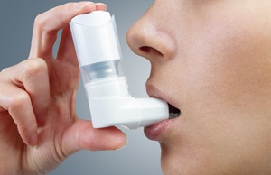 Woman uses an inhaler during an asthma attack, close-up from Shutterstock