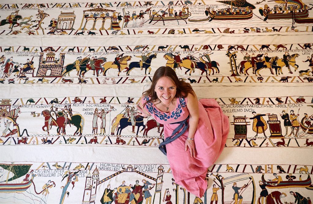 Mia Hansson poses for a photograph with her embroidery replica of The Bayeux Tapestry at the library in Wisbech, east of England on February 24, 2022. Curled up on her sofa in the east of England, former teacher Mia Hansson carefully adds another stitch to her life-size reproduction of the world-famous Bayeux Tapestry. Swedish-born Hansson began the project in 2016, working for several hours a day to reproduce the epic 70-metre (230-foot) embroidery of William the Conqueror's invasion of England. (ADRIAN DENNIS / AFP)