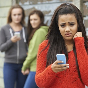 Teenage girl being bullied by text message from Shutterstock