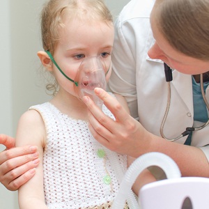 Doctor helps little girl to do inhalation from Shutterstock