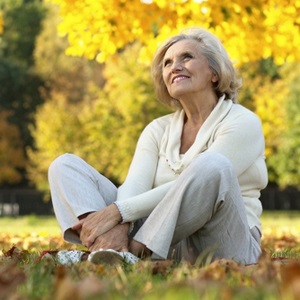 Nice old woman sitting in the autumn park from Shutterstock