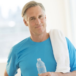 Mature man with towel and water bottle at gym.