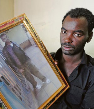 Ethiopian refugee Tagesse Letabo holds up a photograph of his brother, Etebo Kebede, who was shot and killed in his shop. Picture: Ian Carbutt