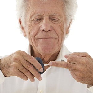 Elderly diabetic man measuring blood sugar levels using glucometer 