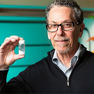 Ronald Evans, director of Salk’s Gene Expression Laboratory, holds a vial with the compound called fexaramine that acts like an imaginary meal. Image: Courtesy of the Salk Institute for Biological Studies.