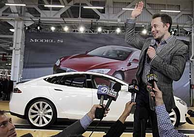 <b>GOOD TIMES, BAD TIMES:</b> Tesla CEO Elon Musk waves during a 2012 rally at the Tesla factory in Fremont, California. On Tuesday (Jan 13 2015) at the Detroit show he said the company was 'on track' despite problems. <i>Image: AP / Paul Sakuma</i>