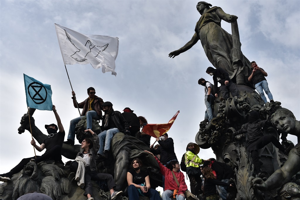 Protesters climb the Triumph of the Republic sculpture at the Place de la Nation during a May Day protest on 1 May 2024 in Paris, France