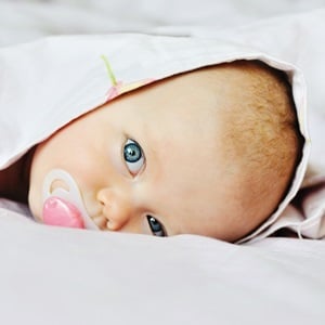 A 3 months old baby looking out under the blanket. (Shutterstock)