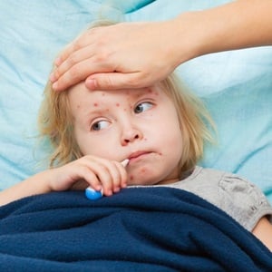 A mother measures the temperature of her sick daughter from Shutterstock