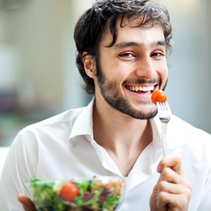 Young man eating a healthy salad from Shutterstock