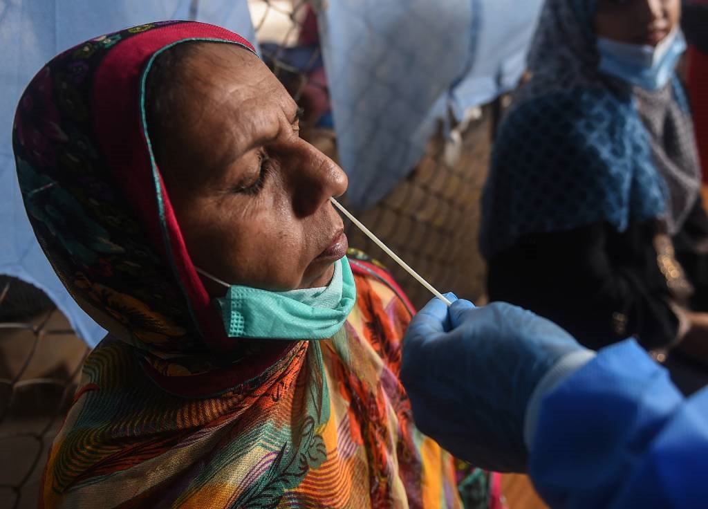 A health official takes a swab sample from a woman to test for the Covid-19 coronavirus at a testing site in Karachi.