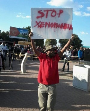 An EFF member holding up a poster against xenophobia walks through Alexandra. (Thomas Hartleb, News24)