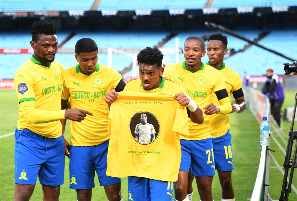 Kermit Erasmus of Mamelodi Sundowns leads the team by holding a jersey with Anele Ngcongca's face as they celebrate the life of the deceased player.