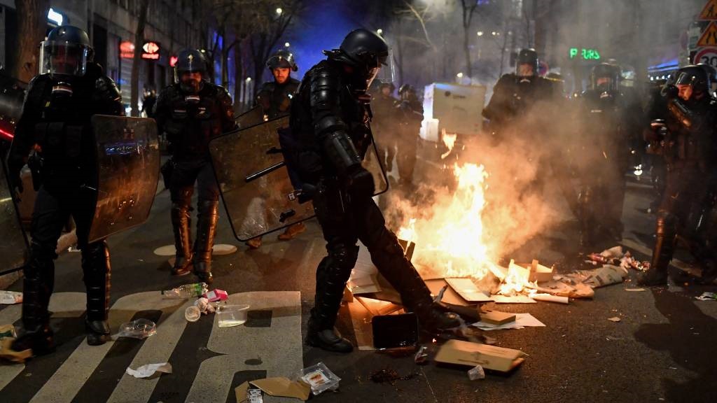 Bir Fransız Jandarma bir gösteri sırasında bir sokak yangını tekmeliyor