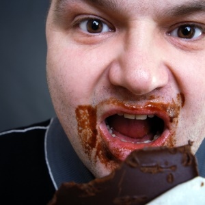 Fat man eating chocolate from Shutterstock