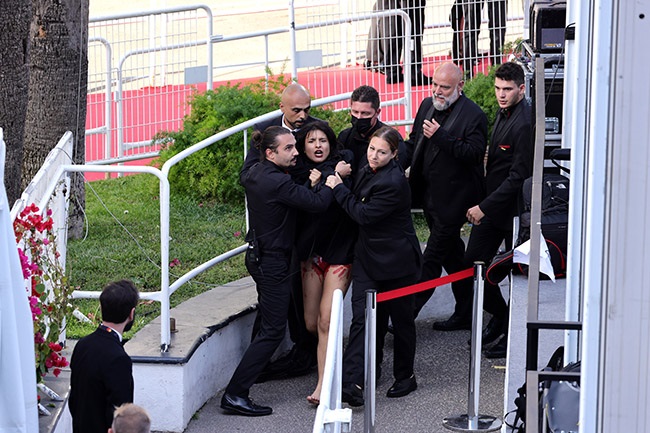 Security remove a protester from the red carpet during the Three Thousand Years Of Longing (Trois Mille Ans A TAttendre) Red Carpet during the 75th annual Cannes film festival.