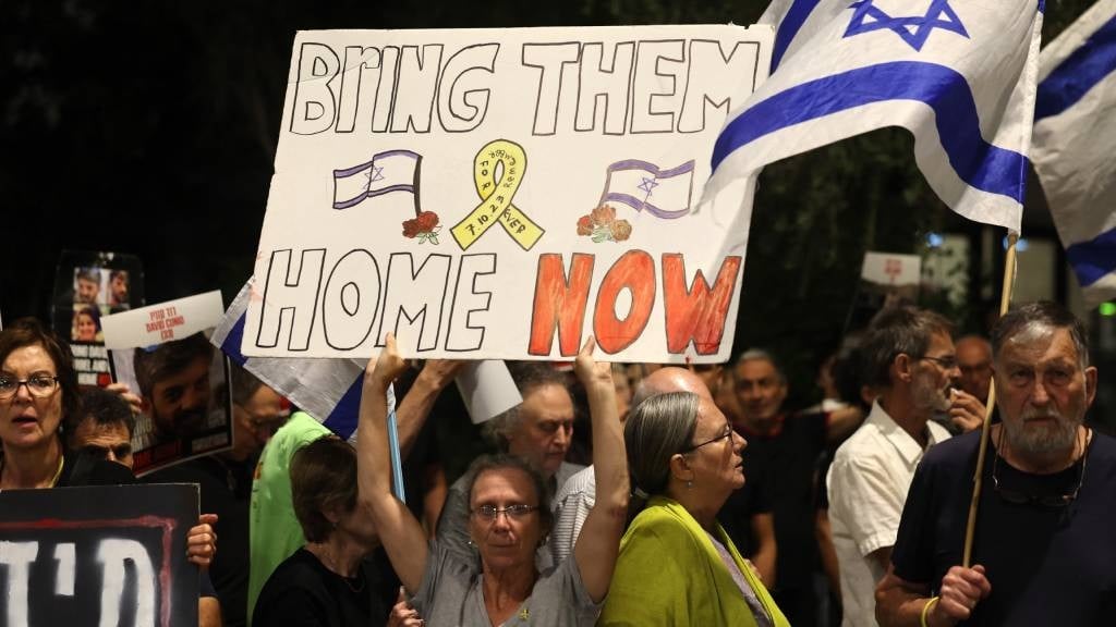 Relatives and supporters raise placards bearing me