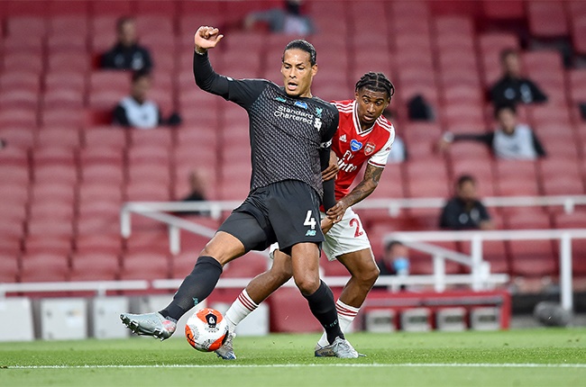 Virgil van Dijk of Liverpool is challenged by Reiss Nelson of Arsenal during the Premier League match between Arsenal FC and Liverpool FC at Emirates Stadium on July 15, 2020 in London, England. Football Stadiums around Europe remain empty due to the Coronavirus Pandemic as Government social distancing laws prohibit fans inside venues resulting in all fixtures being played behind closed doors.