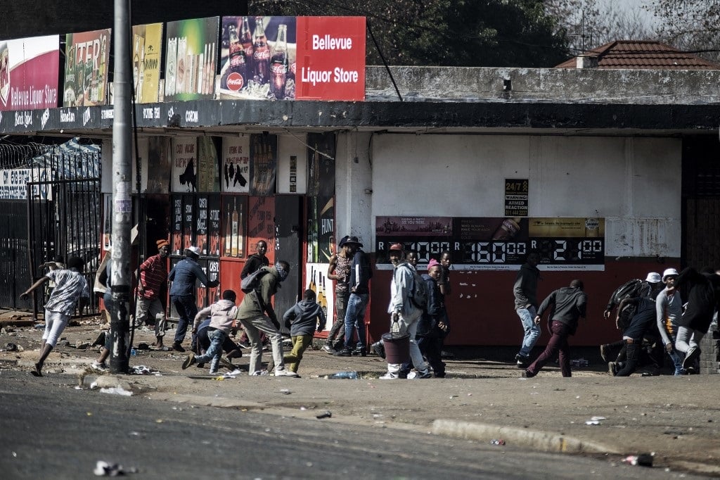 Protesters run away after police officers open fire, using rubber bullets, to disperse the crowd in Jeppestown district, Johannesburg, on July 11, 2021.