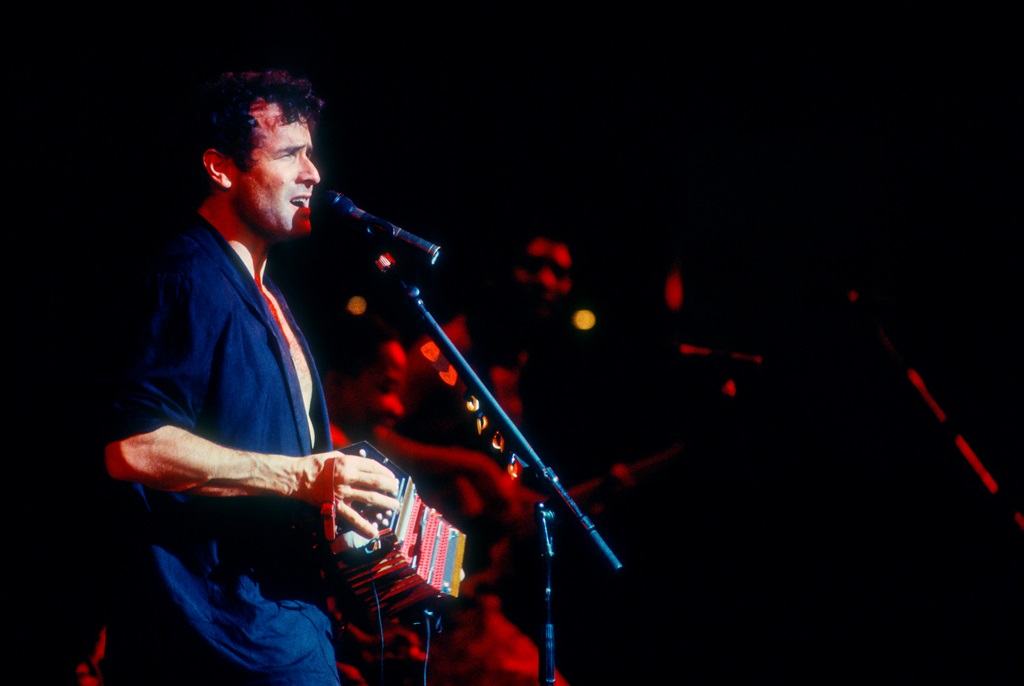South African musician Johnny Clegg plays concertina as he performs, with his band Savuka, at Town Hall, New York, New York, July 14, 1996. (Photo by Jack Vartoogian/Getty Images)